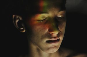 Foto eines Jugendlichen mit geschlossenen Augen, beleuchtet mit einem farbigen Licht